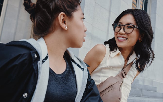 A smiling woman wearing Ray-Ban Meta smart glasses talks to a friend.